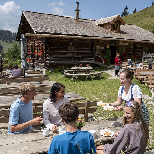 Sennerin serviert einer Familie Bauernkrapfen