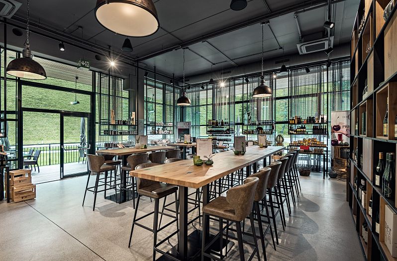 Moderner Restaurantbereich im Großarler Genuss mit langen Holztischen, großen Fensterfronten und Blick ins Grüne.
