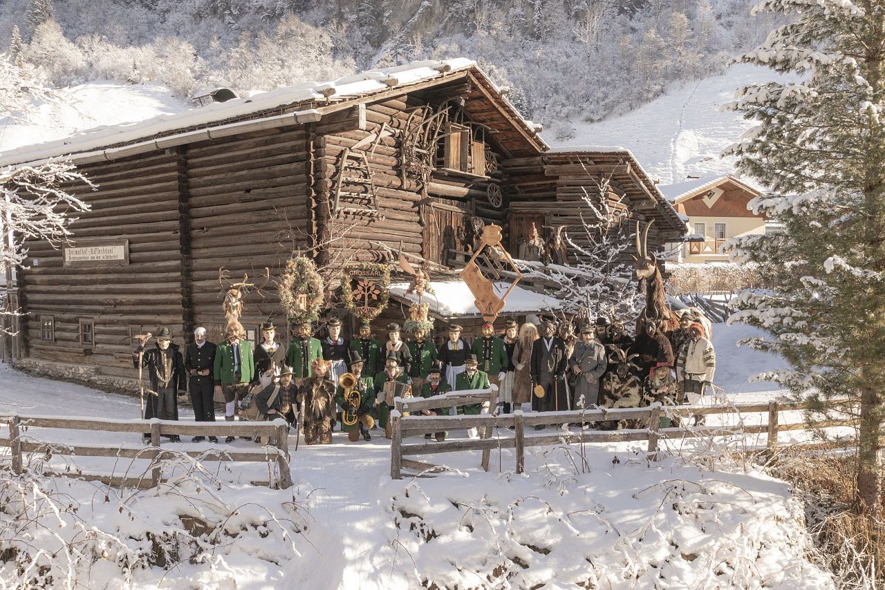 Gruppenfoto vom Perchtenverein Großarl in winterlicher Landschaft vor dem Denkmalhof Kösslerhäusl.