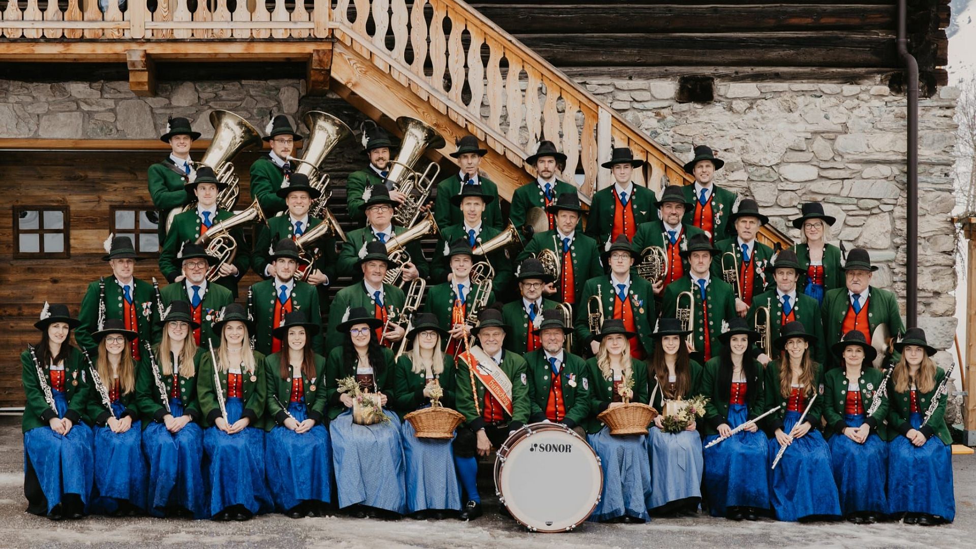 Alle Mitglieder der Trachtenmusikkapelle Hüttschlag stehen in Aufstellung für ein Gruppenbild. Sie tragen alle eine schöne Vereinstracht.