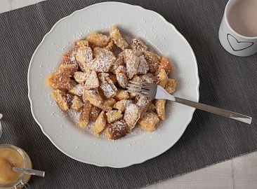 Ein Kaiserschmarrn mit Staubzucker bestreut steht am Tisch.