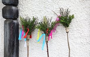 Drei Palmbuschen mit bunten Schleifen sind vor der Kirchenmauer angelehnt.