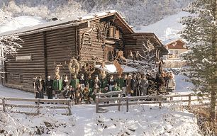Gruppenfoto vom Perchtenverein Großarl in winterlicher Landschaft vor dem Denkmalhof Kösslerhäusl.